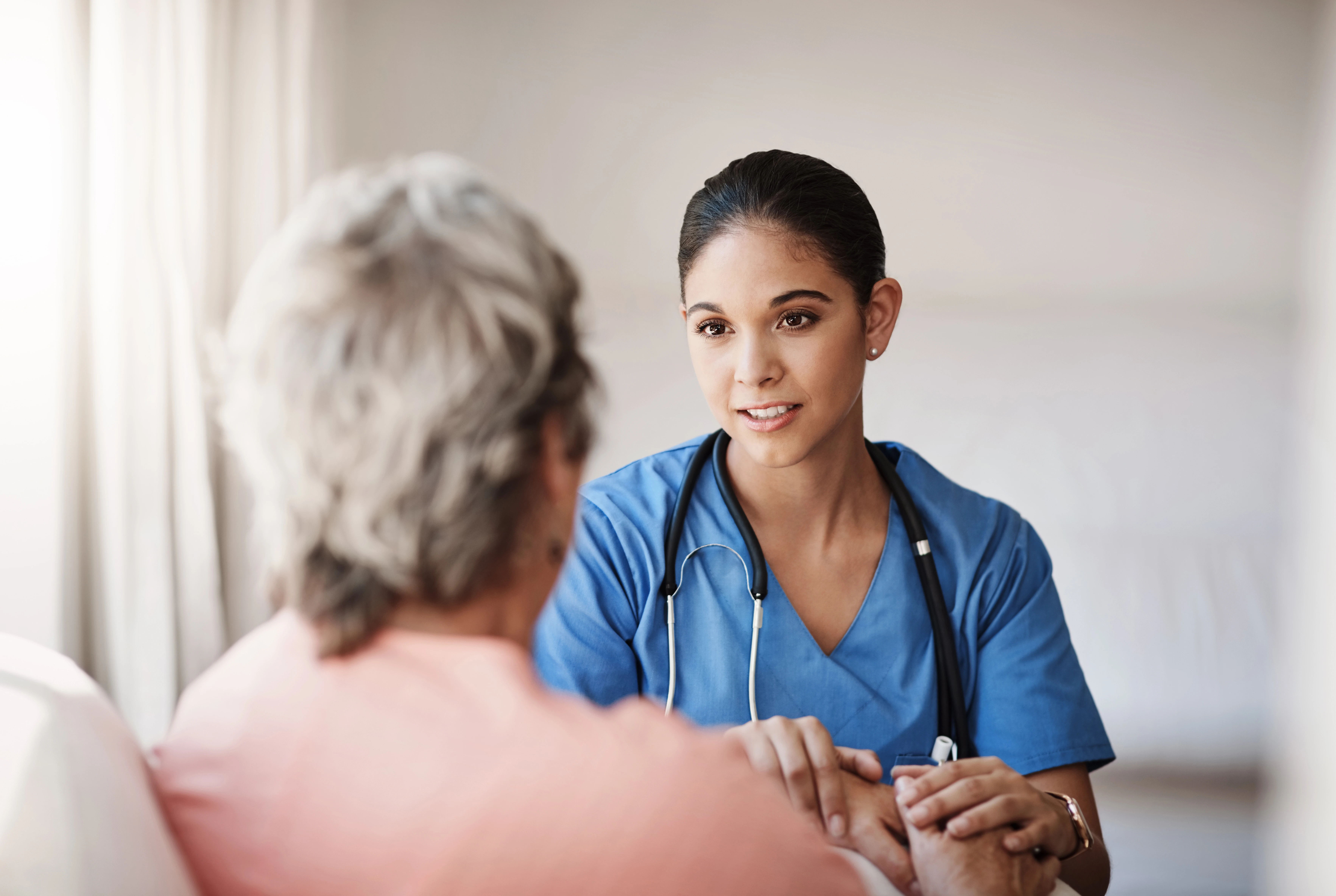 Female medical personnel talking to a older patient. 