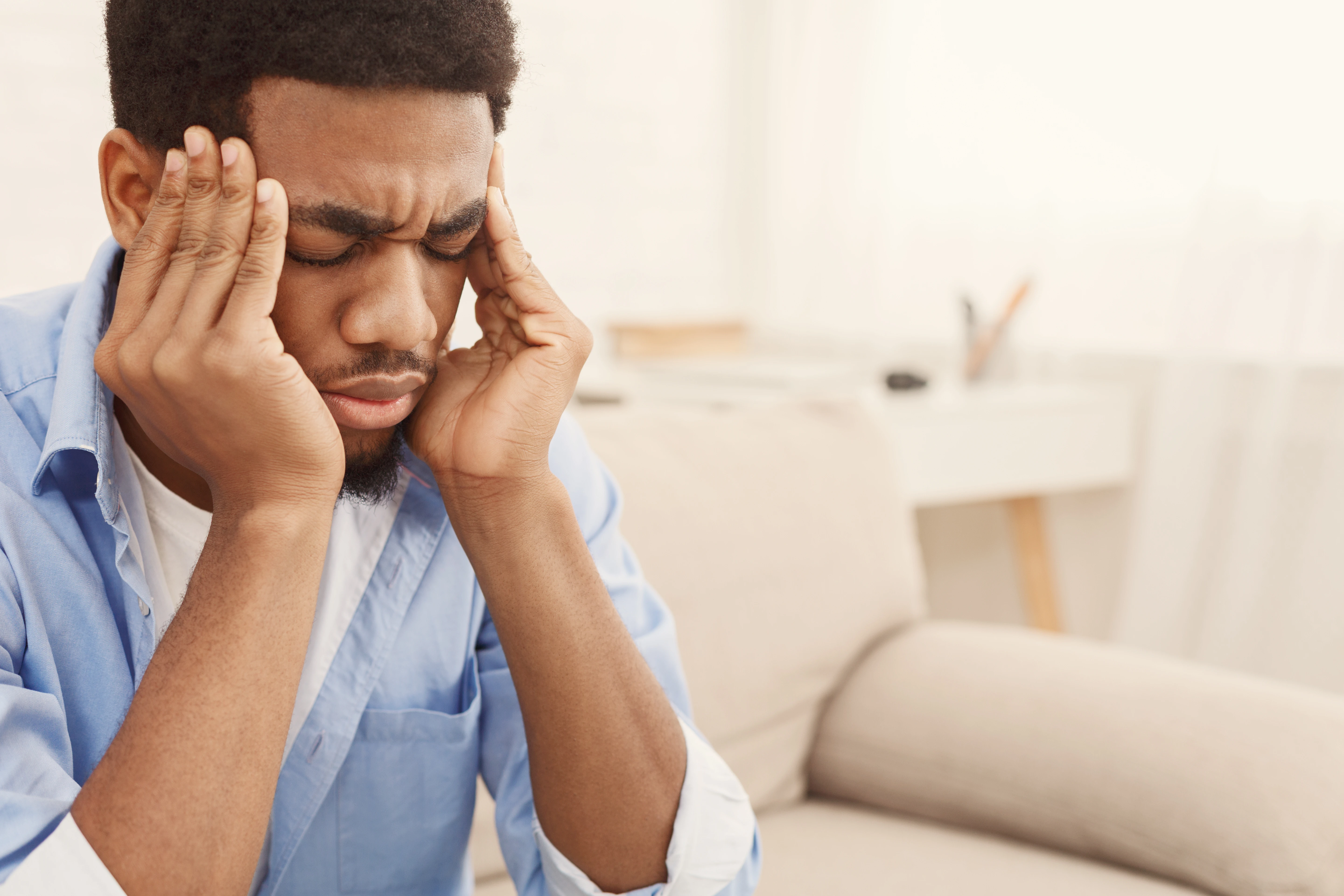 Man rubbing his face and furrowing his brow.