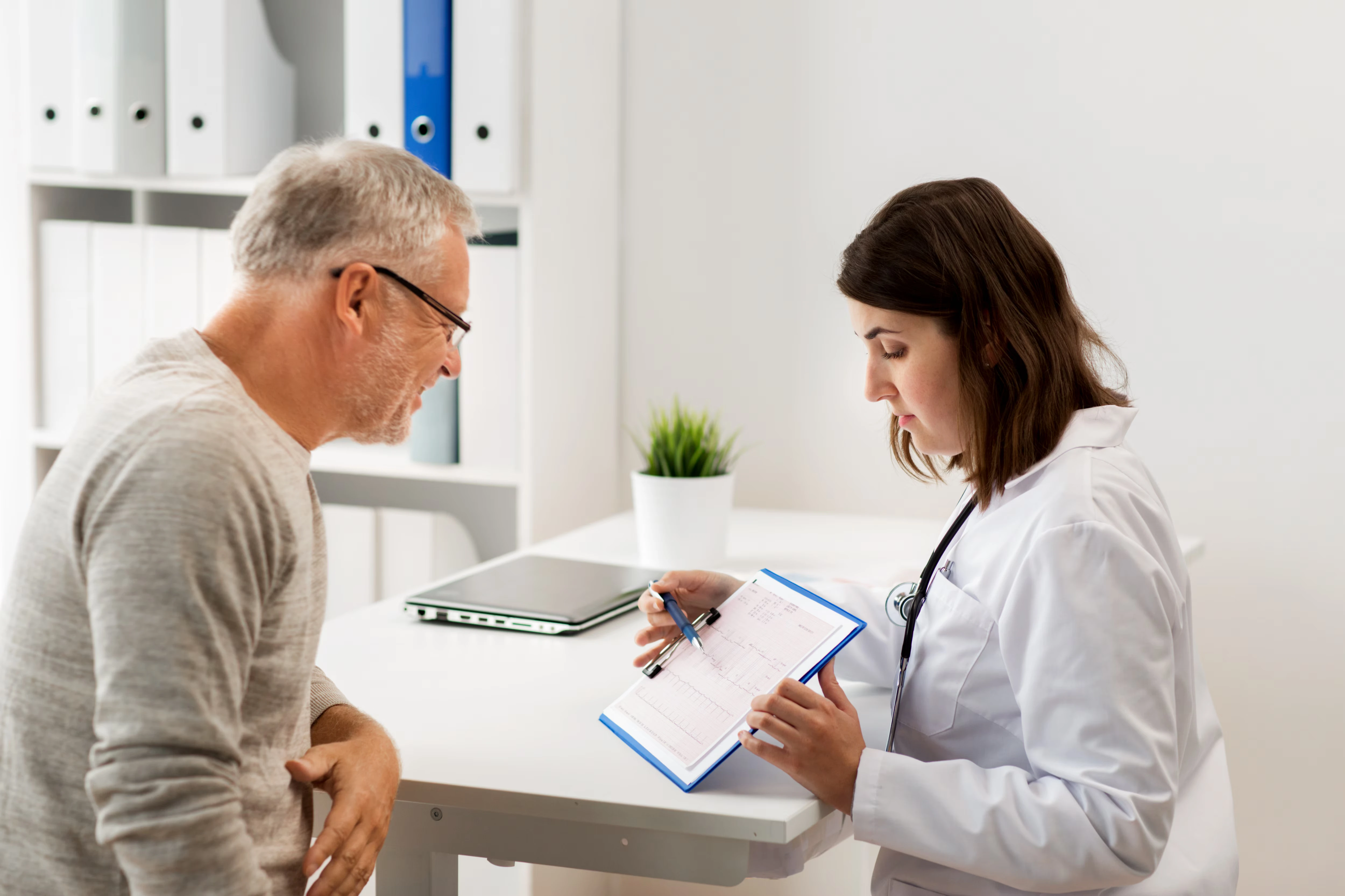 Medical personnel showing test results on a clipboard to a male patient.