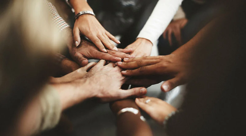 Hands of many skin tones in a huddle