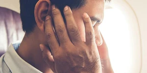 Man holding ears in discomfort